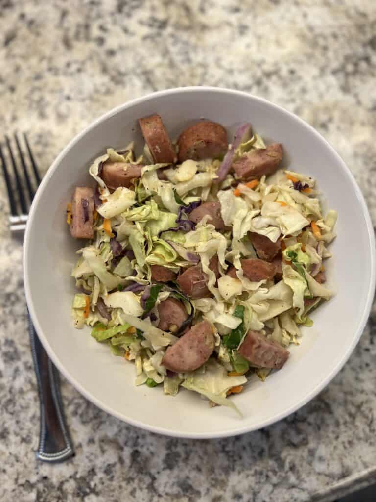 cabbage and sausage in white bowl with fork