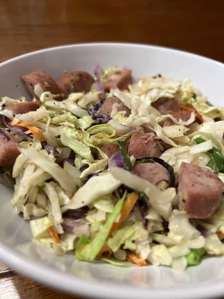 cabbage and sausage in white bowl on wooden table